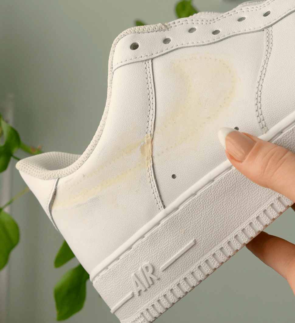 Close up shot of dried repair filler on nike swoosh of Nike Airforce 1 sneakers being held up by a person's hand
