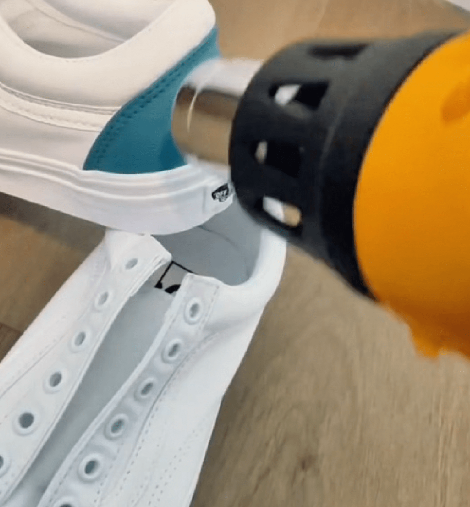 Using a heat gun to set Angelus paint on fabric Vans shoes for a long-lasting finish.