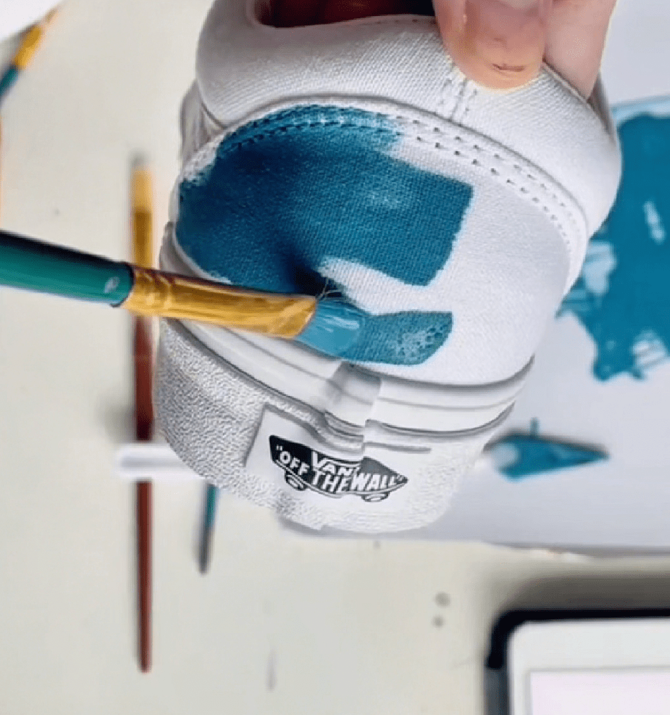 Painting a white canvas shoe with turquoise Angelus Leather Paint using a detail brush.