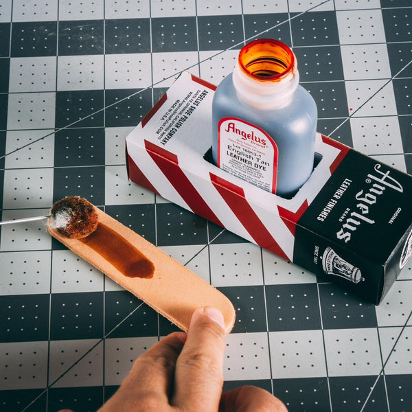 Applying Angelus Leather Dye to a natural leather strip with the bottle dauber