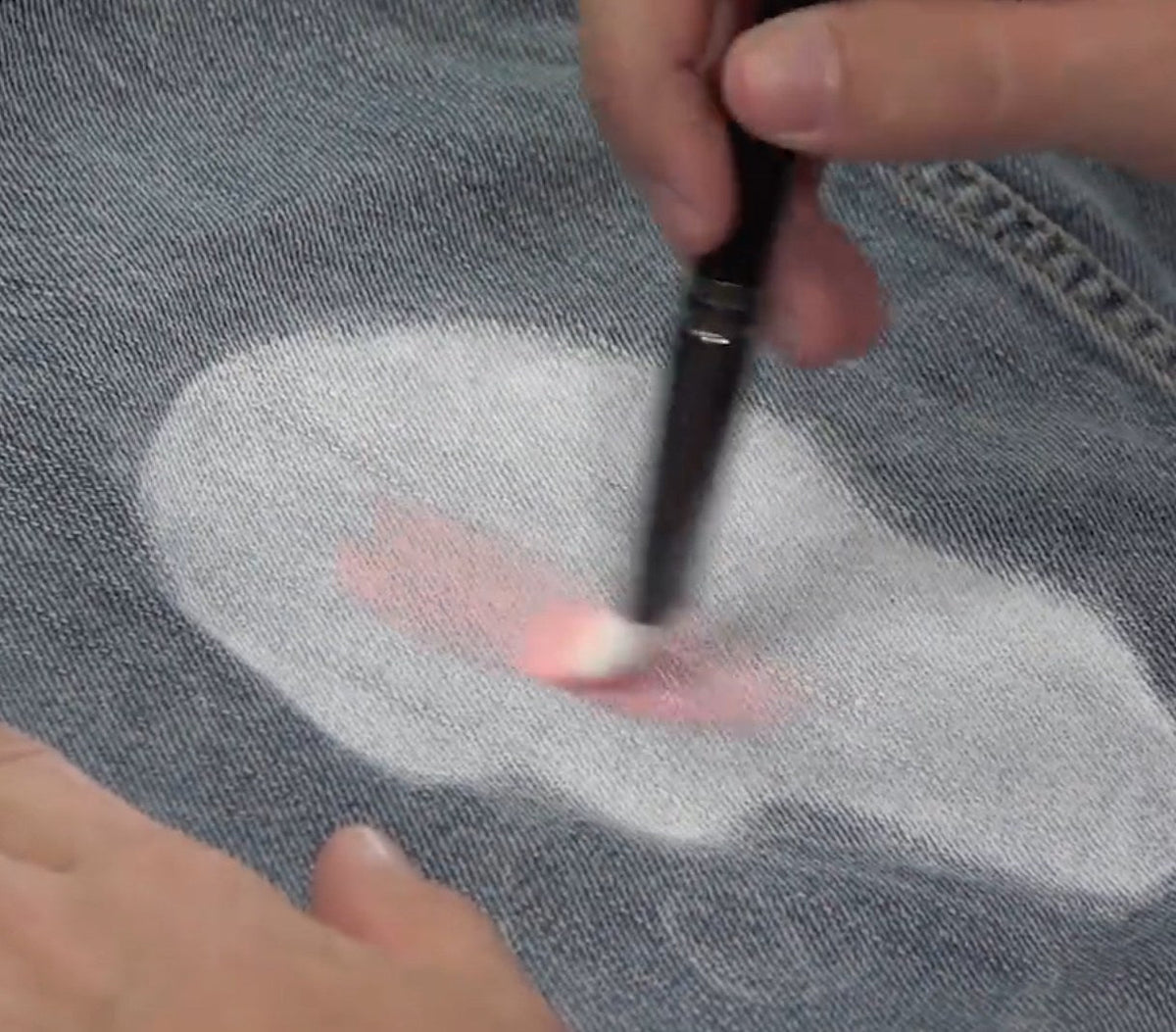 Painting color over a white base on denim with a fine brush