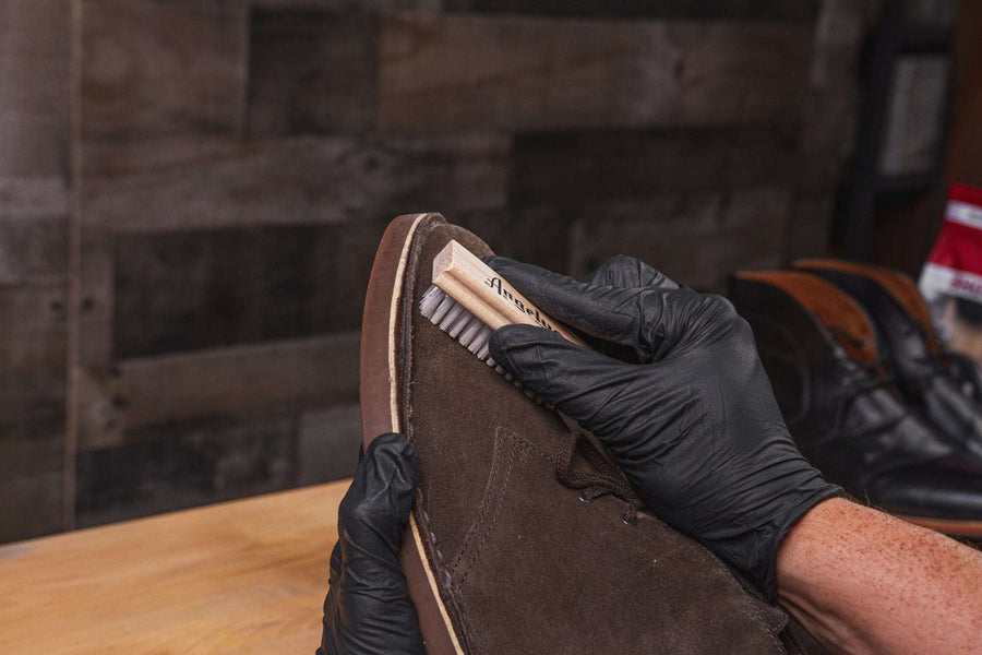 Hand brushing a suede boot after applying suede conditioner.