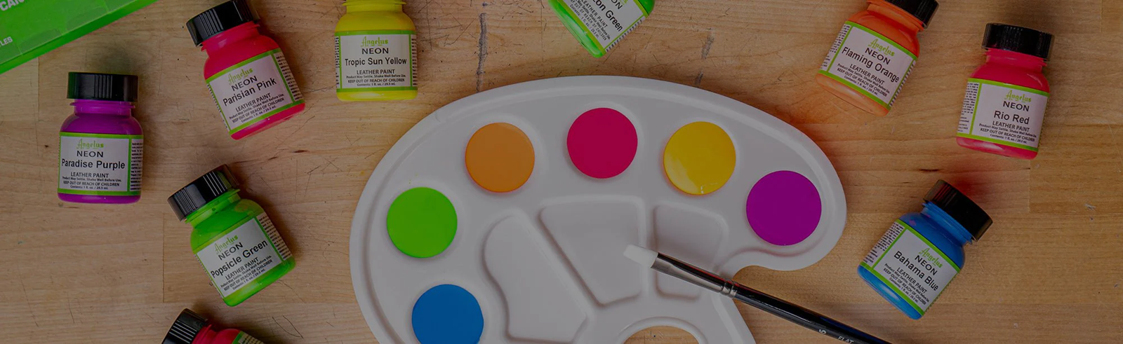 Angelus neon fabric paint bottles with bright color swatches on a paint palette.