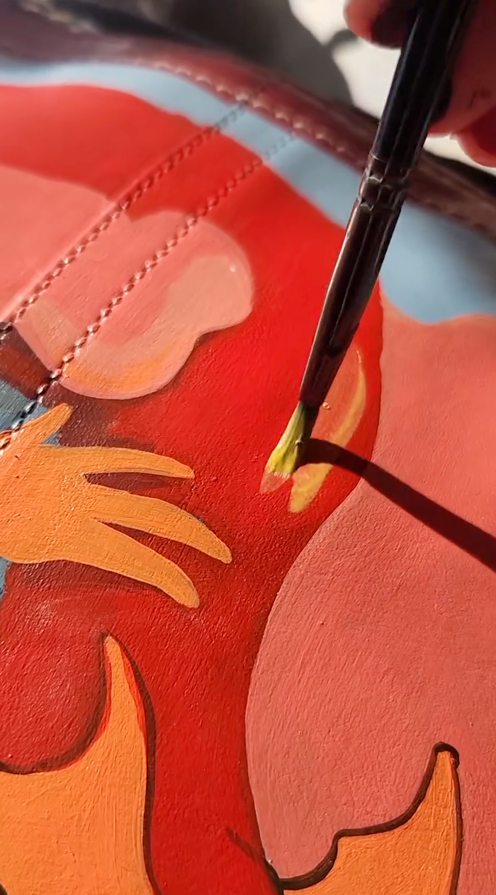 Blending pink and orange Angelus paint for a custom dragon mural