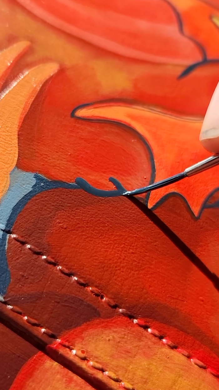 Detailing a custom leather bag with a fine point Angelus paint brush