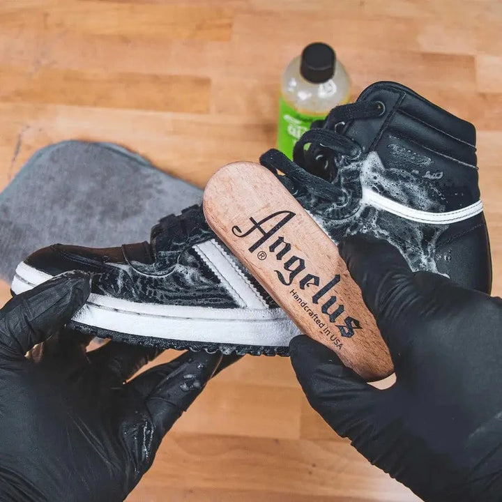 Scrubbing a sneaker sole with an Angelus cleaning brush